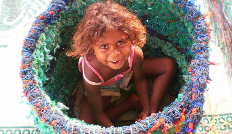 Shekeena Pahimbung easily fits into this basket as it was being made during the first ghost net workshop in Aurukun in 2009. Photo by Sue Ryan.